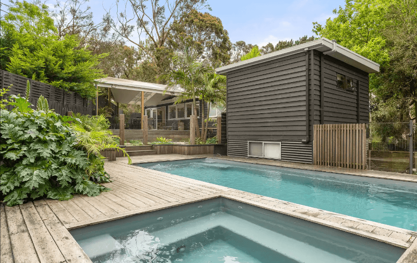 A backyard with a pool and a spa with a pool house.